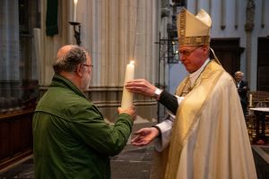 Jos Vriesema neemt namens de parochie de kaars in ontvangst van Mgr. De Korte